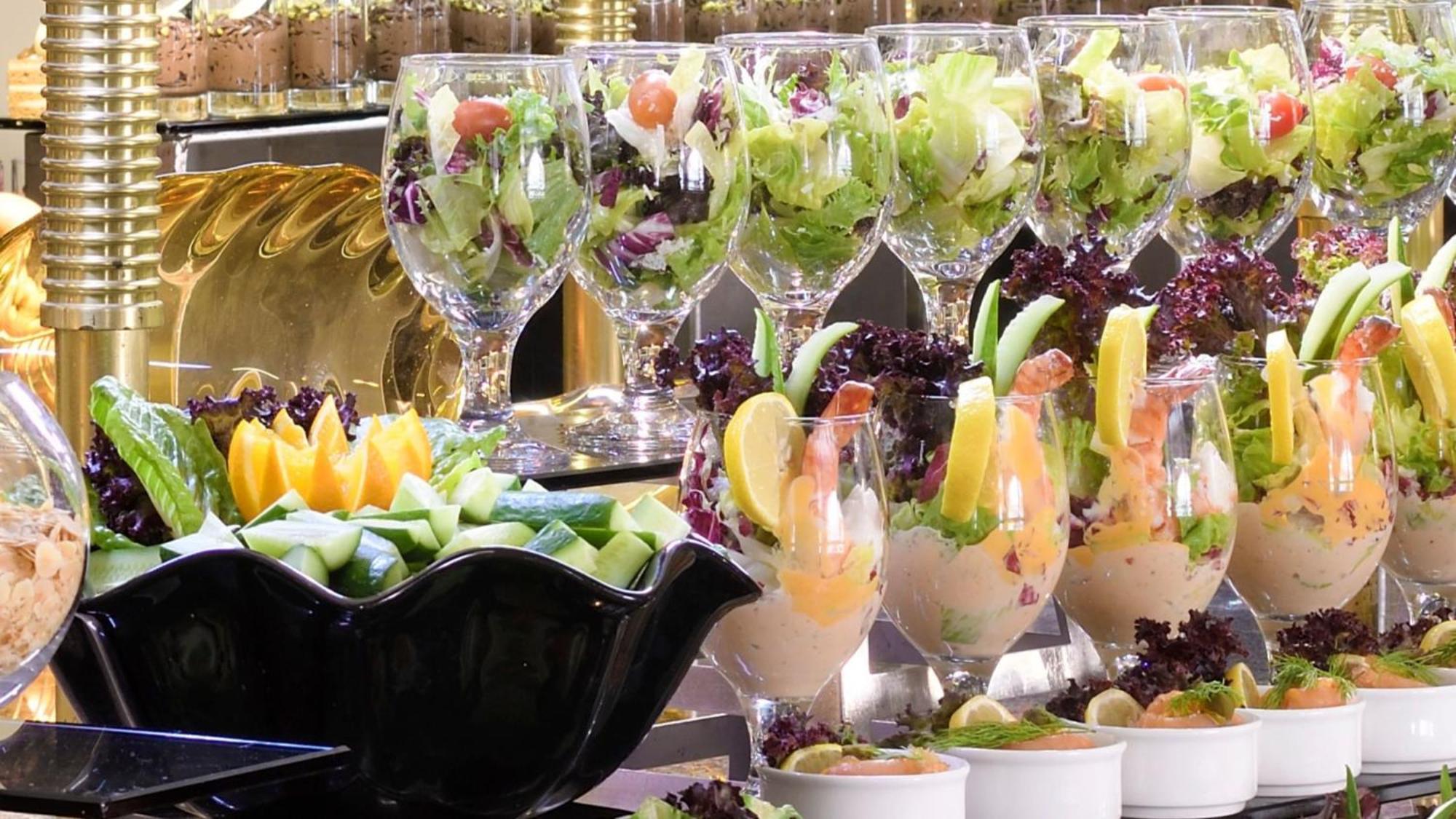 Hotel Intercontinental Dar Al Iman Madinah By Ihg Medyna Zewnętrze zdjęcie The photo features an elegant display of food items. In the background, there are several clear glasses filled with vibrant salads, featuring various types of greens and garnishes. In the foreground, there is a decorative black bowl containing cut pi