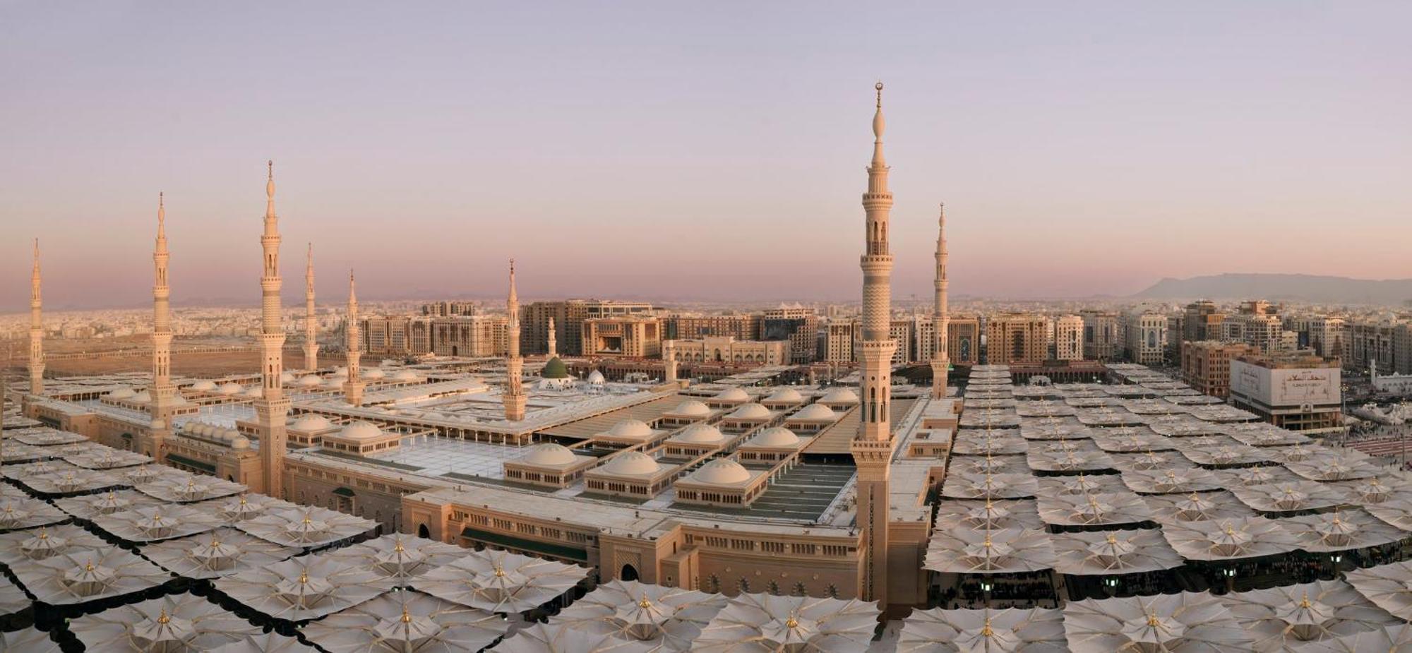 Hotel Intercontinental Dar Al Iman Madinah By Ihg Medyna Zewnętrze zdjęcie The photo shows an aerial view of the Al-Masjid an-Nabawi, or the Prophet's Mosque, located in Medina, Saudi Arabia. The mosque features distinct minarets, large white domes, and expansive open areas with large umbrellas that provide shade for visito