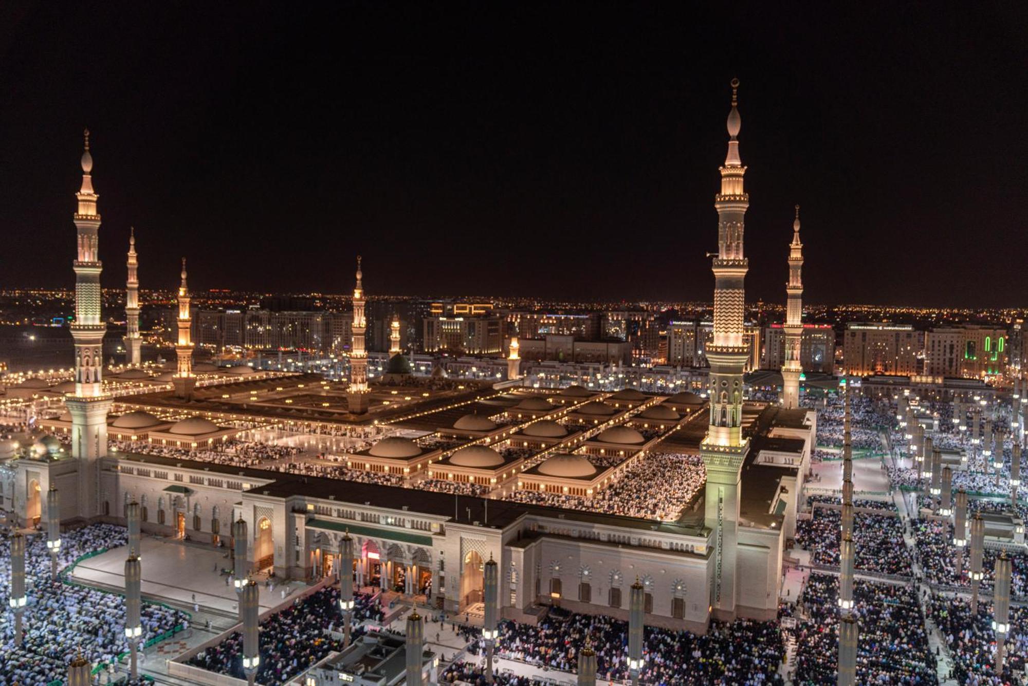 Hotel Intercontinental Dar Al Iman Madinah By Ihg Medyna Zewnętrze zdjęcie The photo shows a panoramic view of a large mosque complex illuminated at night. It features tall minarets with lights, a vast courtyard filled with people, and a beautifully lit architectural design. The overall ambiance suggests a significant space