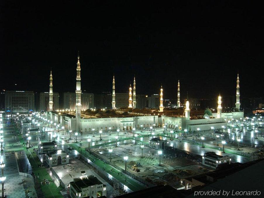 Hotel Intercontinental Dar Al Iman Madinah By Ihg Medyna Wyposażenia zdjęcie The image shows the illuminated landscape of a mosque complex at night. It features several tall minarets, which are typically part of Islamic architecture, adorned with lights. The mosque's central building is also brightly lit, surrounded by an ope