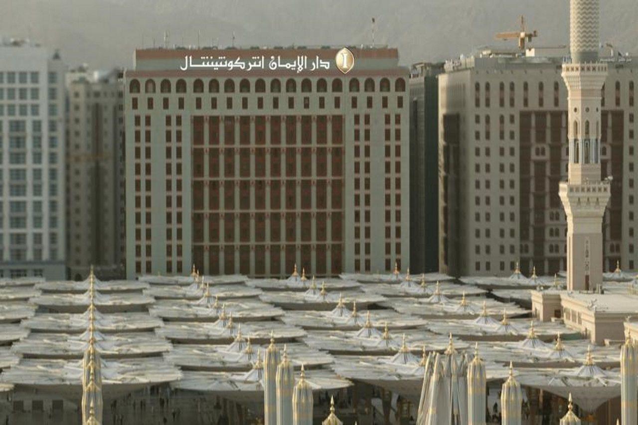 Hotel Intercontinental Dar Al Iman Madinah By Ihg Medyna Zewnętrze zdjęcie The photo shows a view of a large building with a modern architectural design, which appears to be a hotel or a commercial establishment. In front of the building, there are several large white canopies that provide shade, likely in a public space or